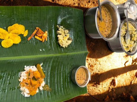Traditional Onam Sadya served on a banana leaf with avial, sambar, vegetable curries, Puli Inji, banana chips and payasam